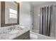 Modern bathroom with granite countertops, a framed mirror and a shower-tub with gray tiling and curtain at 963 Forrest St, Roswell, GA 30075