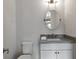 Powder room features an oval mirror, modern fixtures and white cabinets at 963 Forrest St, Roswell, GA 30075