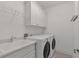 Functional laundry room featuring a sink, quartz countertops, overhead cabinets, and appliances at 963 Forrest St, Roswell, GA 30075
