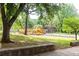 Community playground with yellow and red play structures including slides, swings, and climbing frames surrounded by lush green trees at 79 Anniston Se Ave, Atlanta, GA 30317