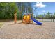 Community playground featuring a blue slide, wooden structure, and pea gravel surface next to a wooded area at 138 Fox Creek Dr, Woodstock, GA 30188
