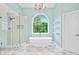 Bright bathroom featuring a glass shower, soaking tub, chandelier, marble floors, and a large window at 5344 Saint Martins Se Ct, Mableton, GA 30126