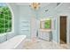 Bright bathroom featuring a soaking tub under a large arched window, chandelier and marble floors at 5344 Saint Martins Se Ct, Mableton, GA 30126