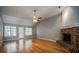 Open-concept living room with hardwood floors, fireplace, and natural light from adjacent door and windows at 135 Greenmont Downs Trce, Alpharetta, GA 30009