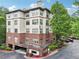 An exterior daytime view of a 4-story building with brick facade and covered parking and a tree-filled landscape at 5559 Glenridge Dr # 1103, Sandy Springs, GA 30342