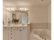 Bathroom featuring double vanity, soaking tub, and white cabinetry at 10898 Gallier St, Johns Creek, GA 30022