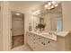 Bright bathroom featuring double sinks, white cabinets, and a view into the walk-in closet at 10898 Gallier St, Johns Creek, GA 30022
