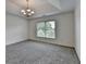 Bedroom with tray ceilings, neutral carpet and decorative chandelier at 10898 Gallier St, Johns Creek, GA 30022