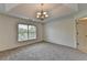 Bedroom with tray ceilings, neutral carpet, a large window, and decorative chandelier at 10898 Gallier St, Johns Creek, GA 30022