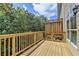 A wooden deck with railings offers an outdoor space, surrounded by trees and blue skies at 10898 Gallier St, Johns Creek, GA 30022