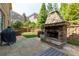Outdoor patio with a stone fireplace, lush greenery, and a grill at 2906 Ansley Manor Ct, Marietta, GA 30062