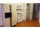 Bright kitchen with white cabinetry, modern appliances, pantry and wood floors adjacent to a staircase at 3416 N Cook Rd, Powder Springs, GA 30127