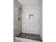 Close up of tiled shower with pebble floor, niche, and modern showerhead at 832 Wyntuck Nw Dr, Kennesaw, GA 30152