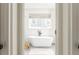 Clean bathroom featuring a freestanding tub, large bright window, and modern neutral decor at 425 Harold Ne Ave, Atlanta, GA 30307