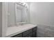 Powder room featuring marble tiling, decorative mirror, modern lighting, and a vanity with a single sink at 1007 Natalie Se Ln, Smyrna, GA 30082