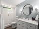 Bathroom featuring vanity with quartz countertop, round mirror and glass-enclosed shower at 12815 Oak Falls Dr, Alpharetta, GA 30009