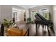 A room with hardwood floors features a piano, neutral colors, and large windows at 12815 Oak Falls Dr, Alpharetta, GA 30009