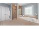 Elegant main bathroom offers a glass shower, soaking tub, and decorative window detail at 12815 Oak Falls Dr, Alpharetta, GA 30009
