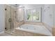 Luxurious main bathroom with glass shower, soaking tub, and travertine tile surround at 1593 Brynwood Nw Ct, Acworth, GA 30101