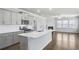 Open-concept kitchen with stainless steel appliances, a quartz island, flowing to living space at 464 Village Ln, Fairburn, GA 30213