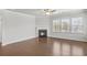 Cozy living room with a fireplace, three windows, and hardwood flooring at 464 Village Ln, Fairburn, GA 30213