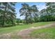 Scenic backyard with mature trees, lush green grass, and a tranquil pond in the background at 170 Elysian Nw Way, Atlanta, GA 30327