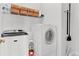 A well-lit laundry room with washer and dryer, and storage shelving at 5335 Davenport Mnr, Cumming, GA 30041