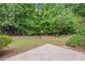 A backyard with a small deck surrounded by a lush green lawn and dense trees at 6131 Windflower Dr, Powder Springs, GA 30127