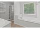 Bright bathroom showcasing a soaking tub, glass-enclosed shower, and a tiled floor at 6131 Windflower Dr, Powder Springs, GA 30127