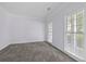 A sunlit room featuring neutral carpeting, fresh paint, and abundant light streaming in through the windows at 6131 Windflower Dr, Powder Springs, GA 30127