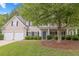 Charming two-story home with a manicured lawn, mature trees, and a welcoming front porch with beautiful landscape at 6131 Windflower Dr, Powder Springs, GA 30127