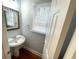 Cozy powder room with a pedestal sink, decorative mirror, and a window at 6131 Windflower Dr, Powder Springs, GA 30127