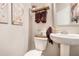 Cozy powder room featuring a pedestal sink, wall art, with a toilet next to a basket of decorative items at 6454 Grey Fox Way, Riverdale, GA 30296