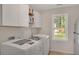 Clean and bright laundry room featuring white cabinets, modern washer and dryer, and a sunlit window at 1050 Chestnut Hill Sw Cir, Marietta, GA 30064