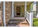 Charming brick front porch with white pillars, a dark wood door, and elegant details for a welcoming entrance at 416 Wilfawn Way, Avondale Estates, GA 30002