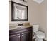 Bathroom with granite countertop, dark wood vanity, decorative mirror, and white toilet at 893 Sandune Dr, Norcross, GA 30093