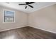 Neutral bedroom features a ceiling fan, window and dark wood-look flooring at 893 Sandune Dr, Norcross, GA 30093