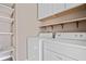 Bright laundry room with washer, dryer, and built-in shelves for storage at 893 Sandune Dr, Norcross, GA 30093