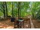 Wooden back deck featuring grill, glass top table and seating; surrounded by mature trees at 1025 Taylor Oaks Dr, Roswell, GA 30076
