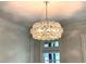 Close up of a round, tiered crystal chandelier hanging from a ceiling with decorative molding above a window at 310 Anders Path, Marietta, GA 30064