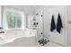 Bright bathroom with a soaking tub under a window and glass enclosed shower with black hardware at 1126 Gate Post Ct, Powder Springs, GA 30127
