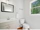 Bathroom with vanity, toilet, wood flooring, and a window with a view of the outside at 1126 Gate Post Ct, Powder Springs, GA 30127