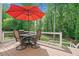 Outdoor seating area with table, chairs, red umbrella, and wooded surroundings at 1126 Gate Post Ct, Powder Springs, GA 30127