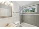 Bright bathroom featuring white wainscoting, gray tile, and a window for natural light at 1281 Snapfinger Rd, Decatur, GA 30032