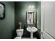 Stylish half bathroom with dark green walls, a pedestal sink, and a modern mirror at 2450 Norwood Park Xing, Atlanta, GA 30340