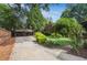 Well-maintained driveway leading to a covered parking area, surrounded by lush greenery and a garden arch at 26 Clarendon Ave, Avondale Estates, GA 30002