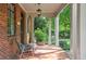 Relaxing front porch featuring red brick, stately columns, and views of the garden at 26 Clarendon Ave, Avondale Estates, GA 30002