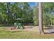 Community playground with green play structures and a grassy area surrounded by trees at 26 Clarendon Ave, Avondale Estates, GA 30002