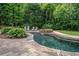 Backyard featuring a stone-lined pool and seating area, surrounded by mature trees, creating a relaxing outdoor oasis at 351 Old Orchard Ct, Marietta, GA 30068