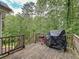 Back deck with lots of lush green trees surrounding the home, an outdoor grill, and stairs to the yard at 505 Blake Dr, Douglasville, GA 30134